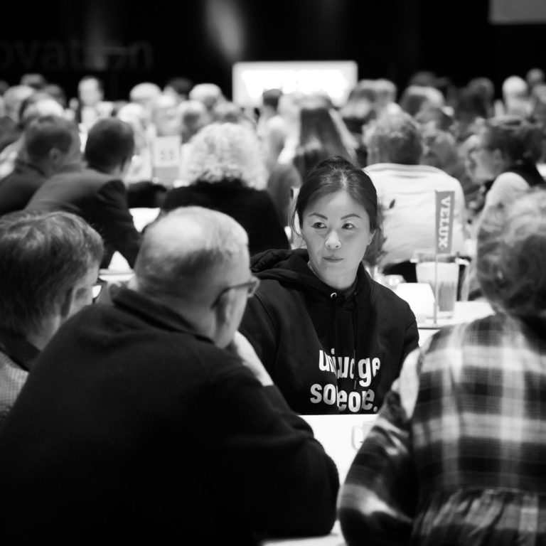 An open book in the Human Library sitting at a table with a group of five readers.
